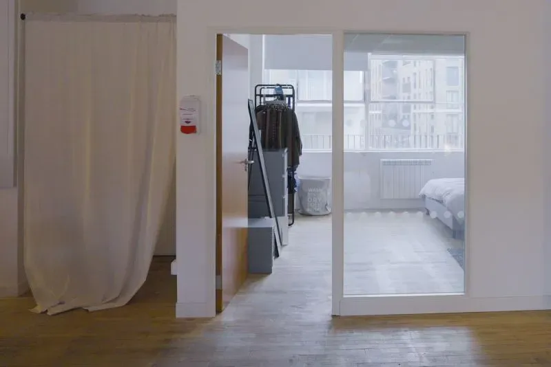 غرفة بسيطة في منزل مشترك بلندن، تحتوي على سرير وواجهة زجاجية، تمثل نمط الحياة بخصائص سهلة المعيشة في ظل ارتفاع الإيجارات.