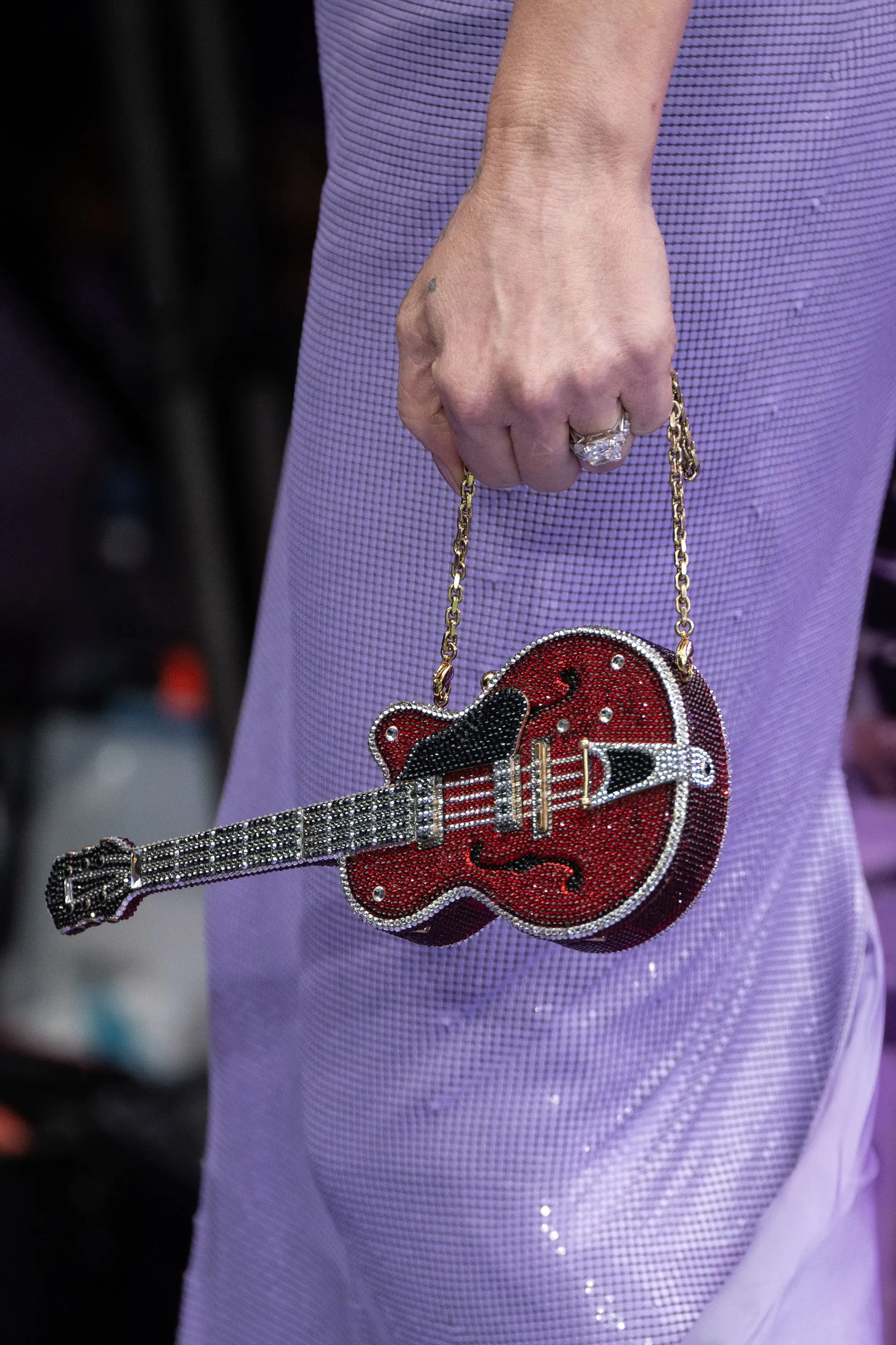 حقيبة متلألئة على شكل غيتار تحملها لوهان، ترتدي فستاناً خزامياً، في عرض فيلم "فريكي فرايدي فرايدي" بلندن.