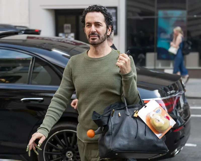 مارك جاكوبس يحمل حقيبة جلدية سوداء من هيرميس بيركين مزينة بلعبة لابوبو، أثناء دخوله مكتبة نيويورك العامة.