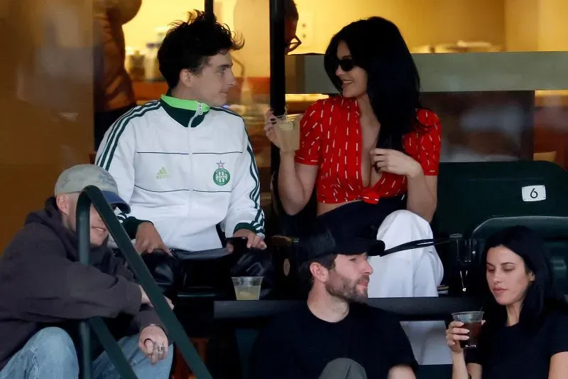 سيلينا غوميز وبيني بلانكو يجلسان في حديقة ماديسون سكوير غاردن، يرتديان أزياء متناسقة بألوان دافئة، أثناء مشاهدتهما مباراة كرة السلة.