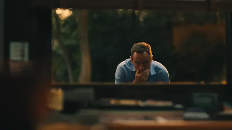 مشهد من مسلسل "اللوتس الأبيض" يظهر شخصية تيموثي، الذي يبدو قلقاً ومتوتراً، بينما ينظر من نافذة.