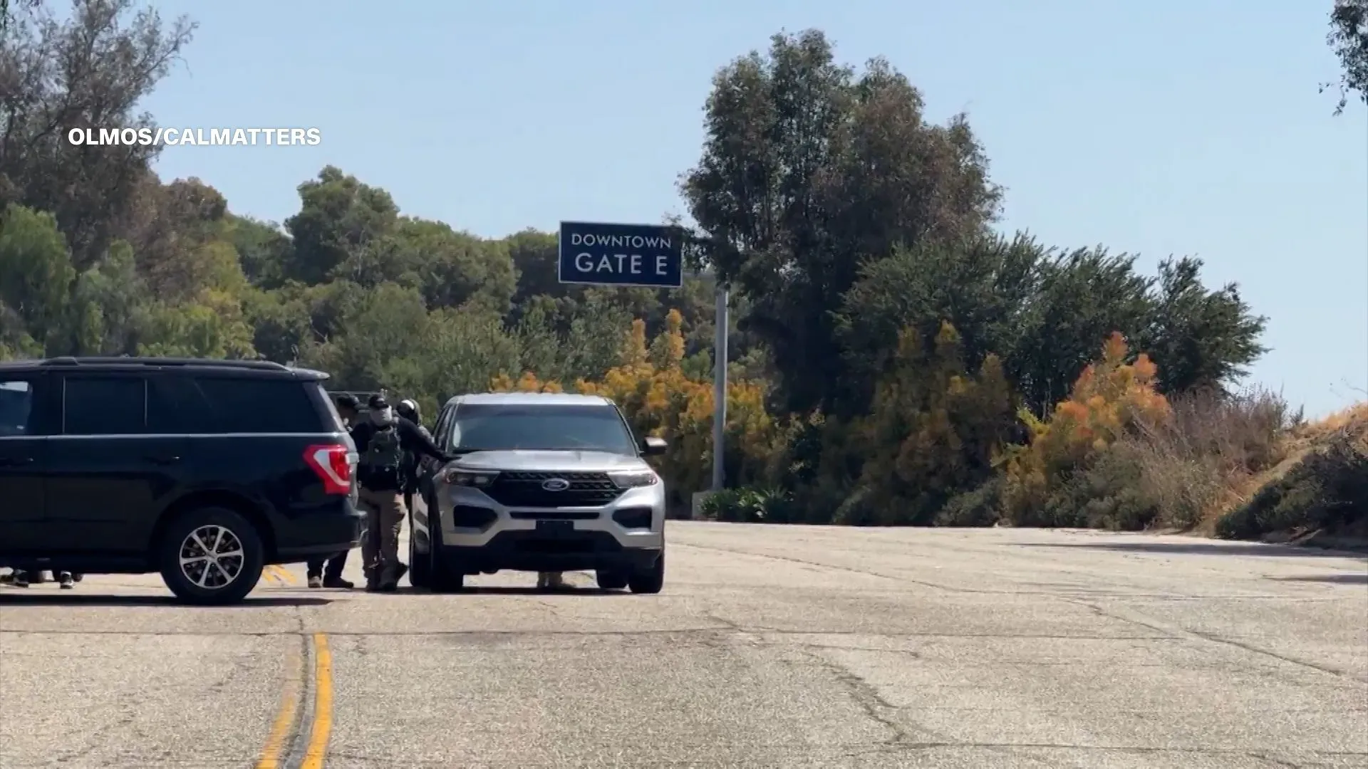 عملاء من وكالة إنفاذ قوانين الهجرة والجمارك الأمريكية يقفون عند مدخل ملعب دودجر، مع وجود سيارات في الخلفية، في سياق مداهمات الهجرة الأخيرة.