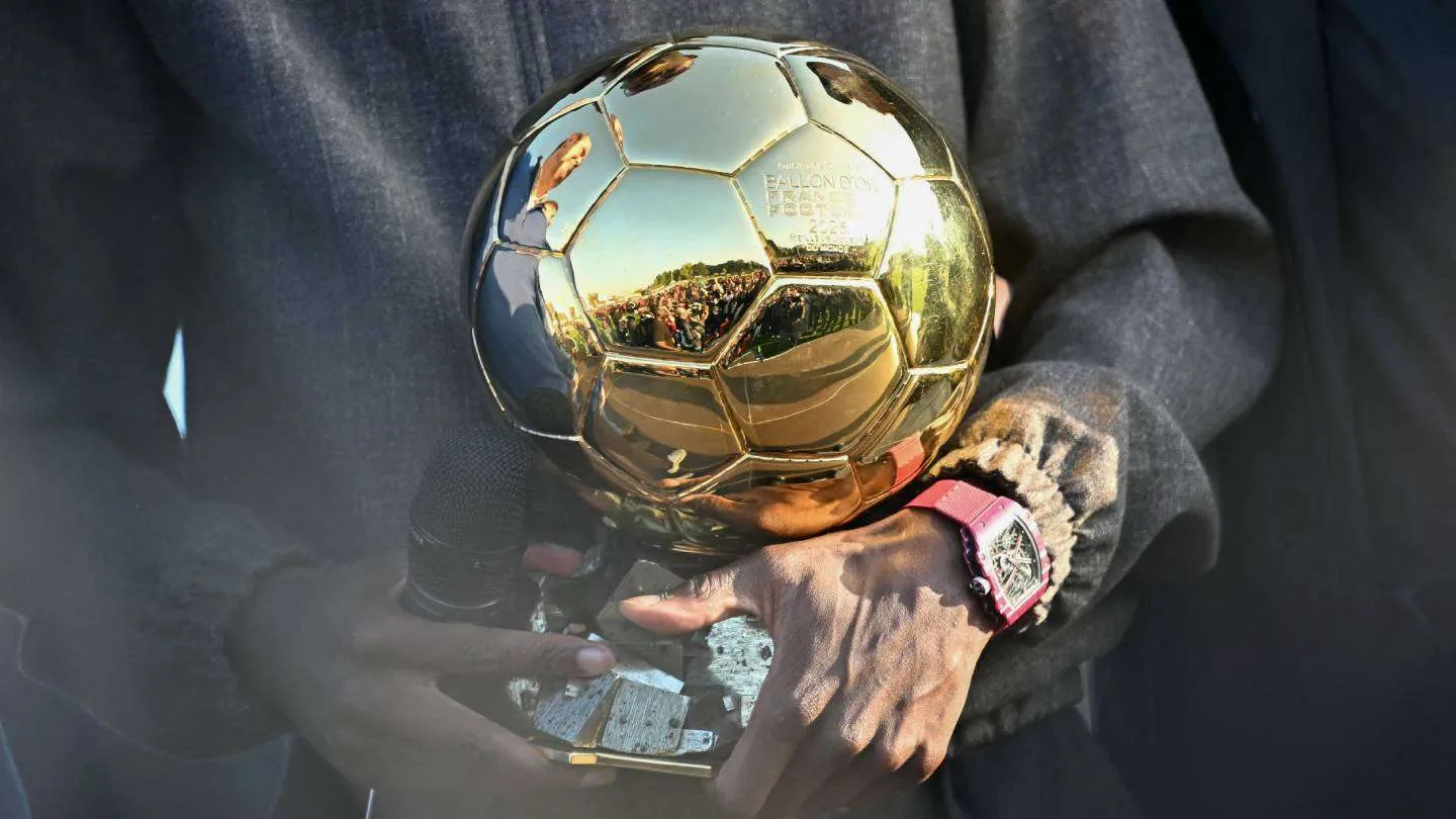 يد تحمل جائزة الكرة الذهبية الذهبية اللامعة، رمز التميز في كرة القدم العالمية وترشيحات 2026.