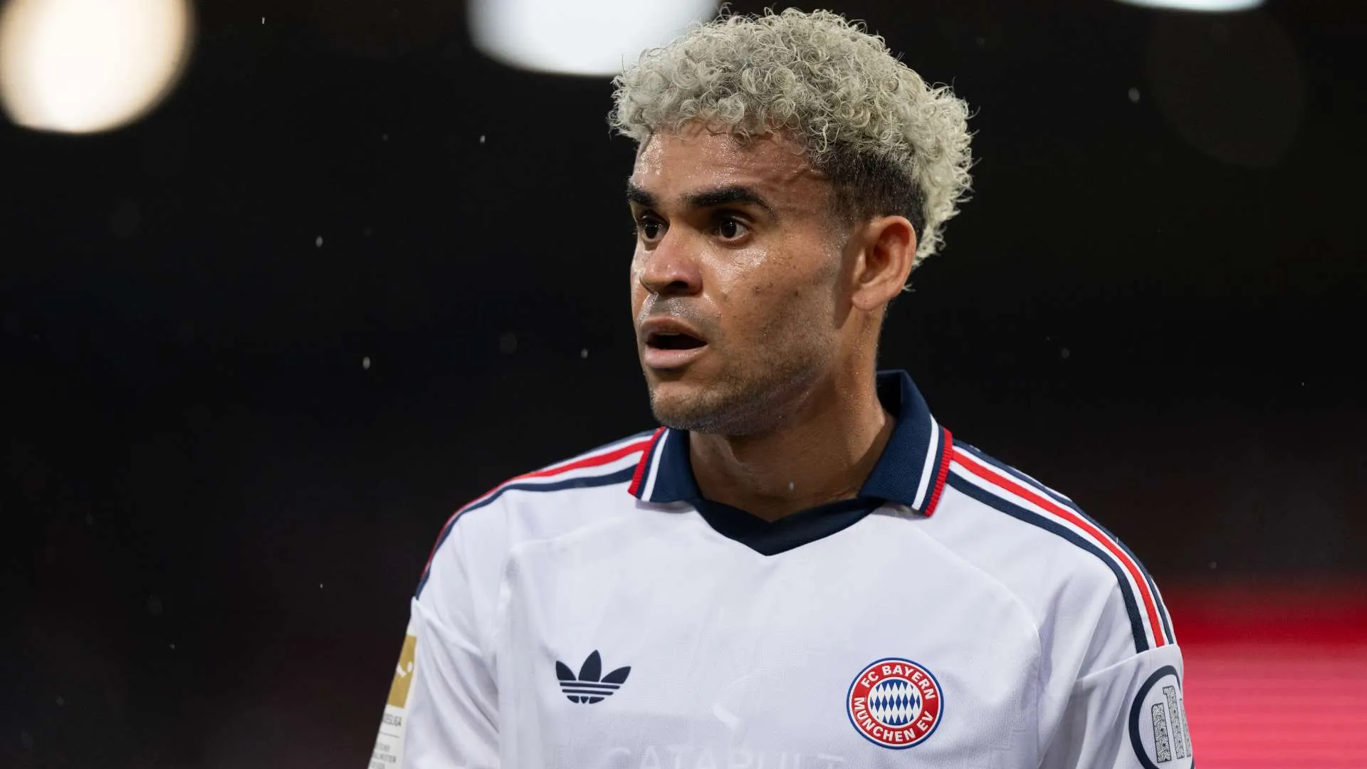 لاعب كرة القدم لويس دياز يرتدي قميص بايرن ميونخ الأبيض خلال مباراة، مع تركيز على وجهه وتعبيره في موسم 2026-27.