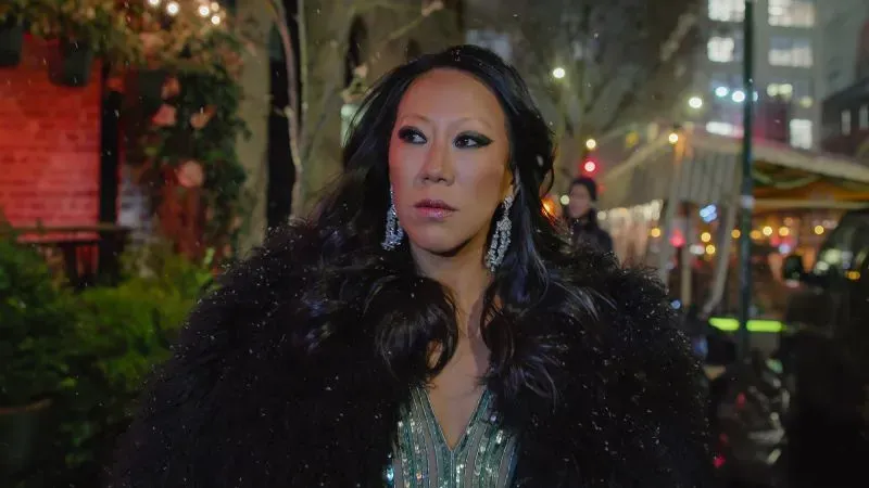 تظهر لين بان مرتدية فستاناً أنيقاً وتستعرض مجوهراتها، وسط أجواء مدينة نيويورك الليلية. كانت مصممة مجوهرات معروفة وعضوة في مسلسل "بلينغ إمباير".