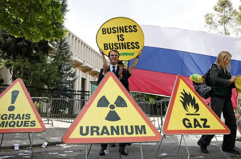 نشطاء منظمة السلام الأخضر يحتجون أمام السفارة الروسية في باريس، حاملين لافتات تنتقد استمرار التجارة مع روسيا، بما في ذلك الغاز واليورانيوم.