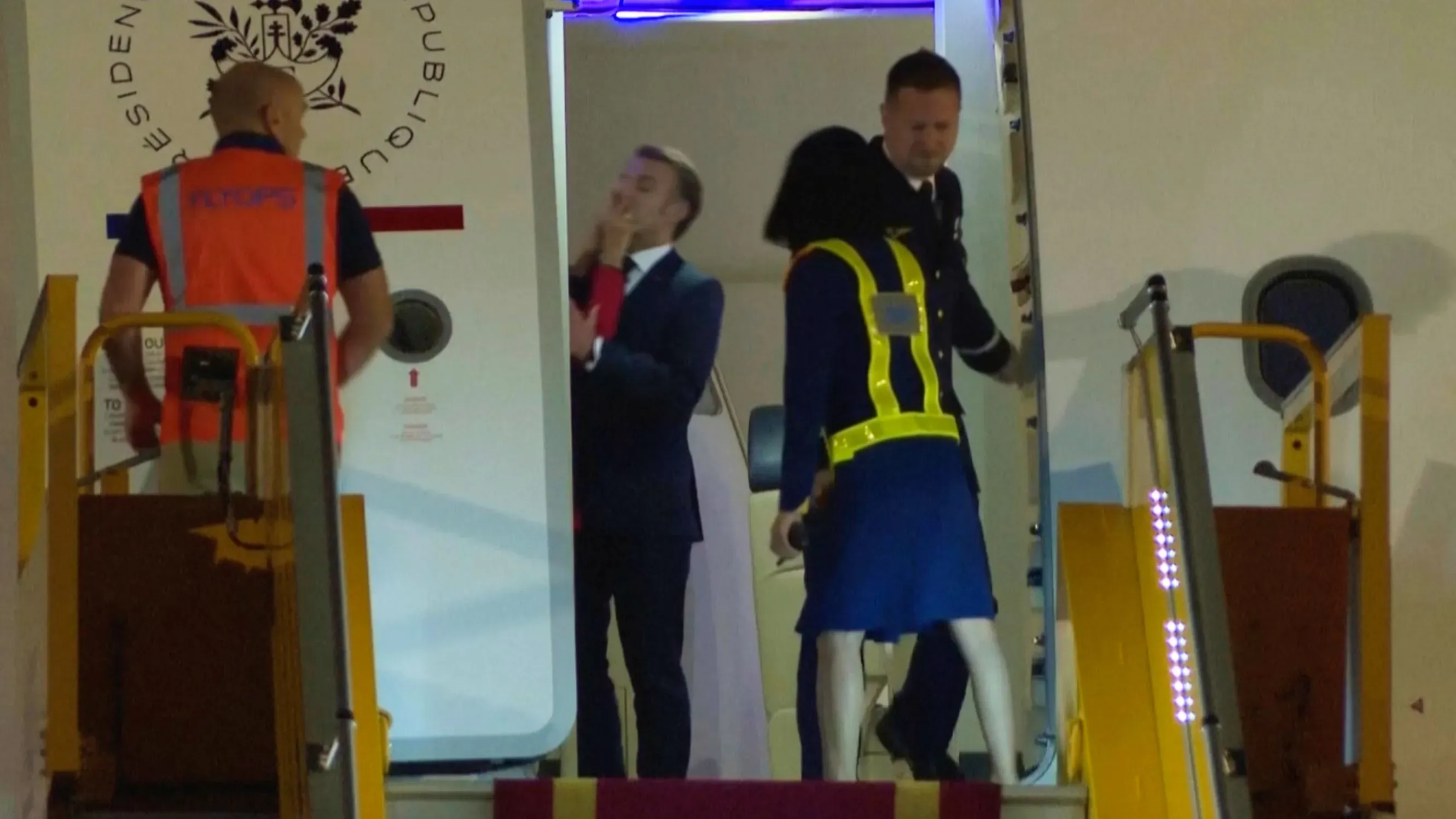 ماكرون يتحدث مع زوجته بريجيت قبل مغادرته الطائرة خلال زيارة إلى فيتنام، في لحظة تعكس التوترات الإعلامية حول حياتهم الشخصية.