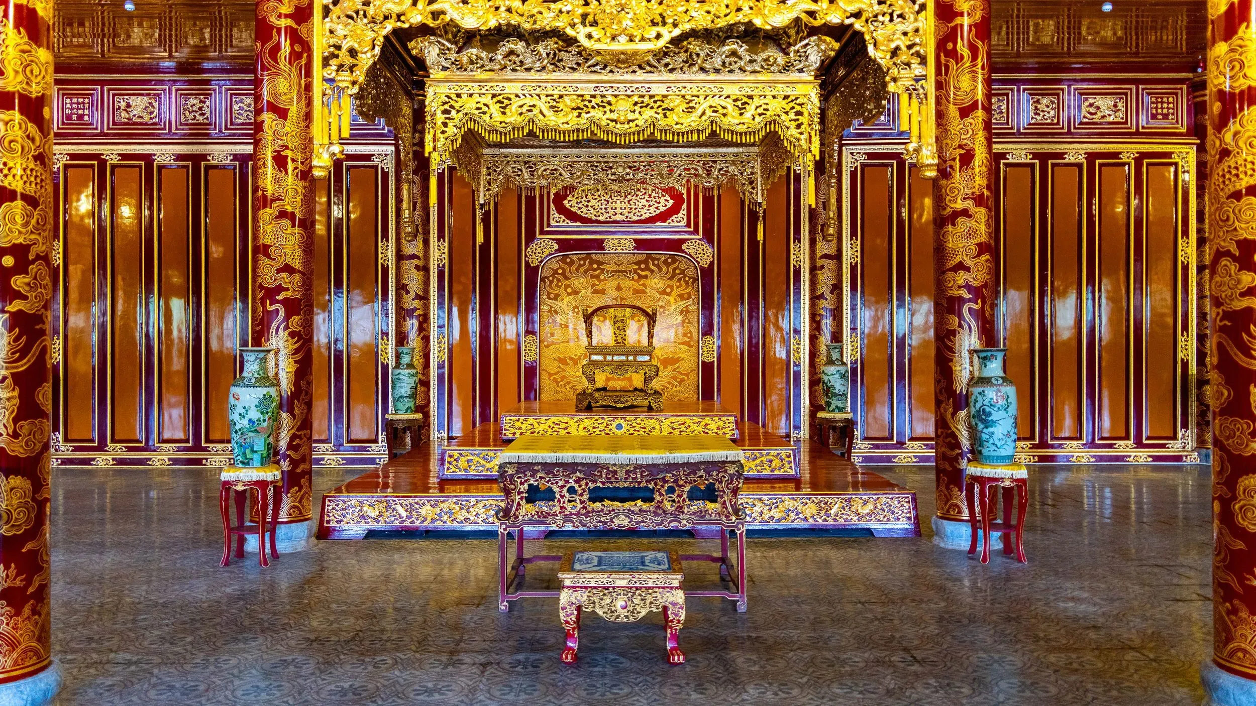 مسند ذراع عرش فيتنامي قديم مكسور، يظهر رأس تنين ملقى على الأرض، داخل قصر ثاي هويا، مع تفاصيل فنية غنية.