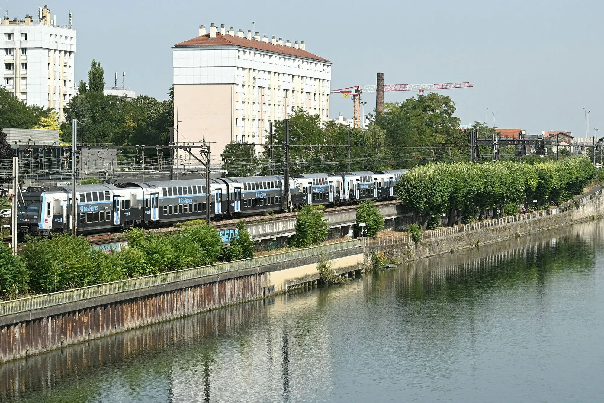 مشهد لنهر السين في باريس مع قطار يمر فوقه، محاط بمباني وأشجار، يشير إلى موقع اكتشاف جثث أربعة رجال.