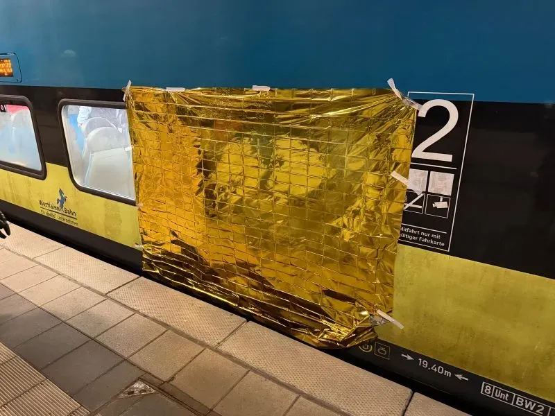 غطاء إنقاذ ذهبي يغطي نافذة قطار في محطة ليرته، حيث كانت عملية إنقاذ رجل عالق تحت مسند ذراع القطار جارية.