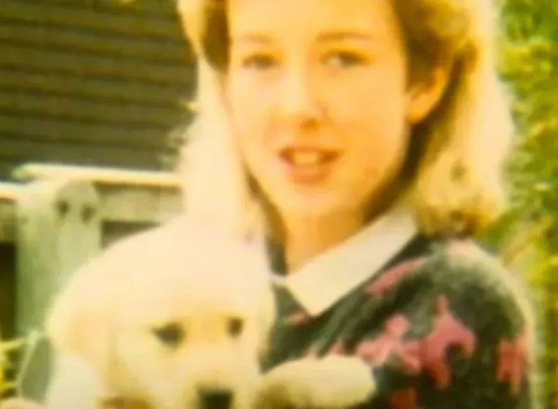 صورة شابة تحمل جروًا، تعكس لحظة من السعادة والبراءة، تتعلق بقضية القتل التي أثرت على عائلتين.