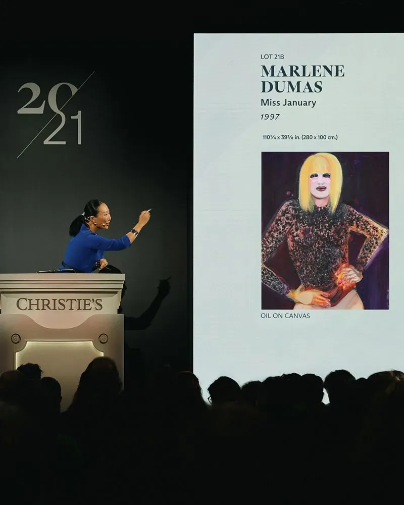 تظهر امرأة تعبر عن الحماس في مزاد كريستيز، حيث تُعرض لوحة "الآنسة يناير" للفنانة مارلين دوماس، التي بيعت بمبلغ قياسي.