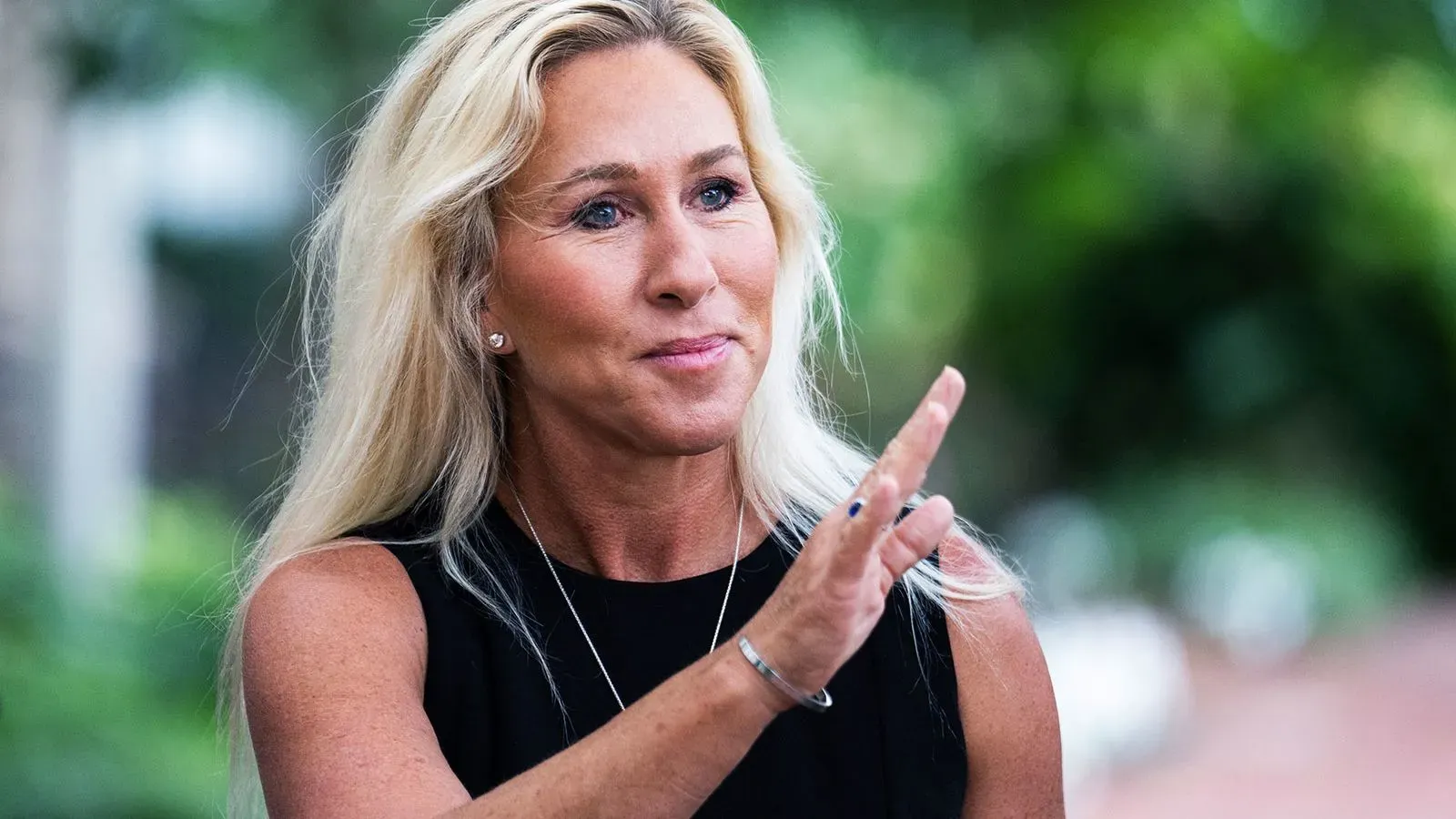 تظهر مارجوري تايلور غرين وهي تتحدث، مع خلفية خضراء، في سياق تغطية التهديدات ضد أعضاء الكونغرس.