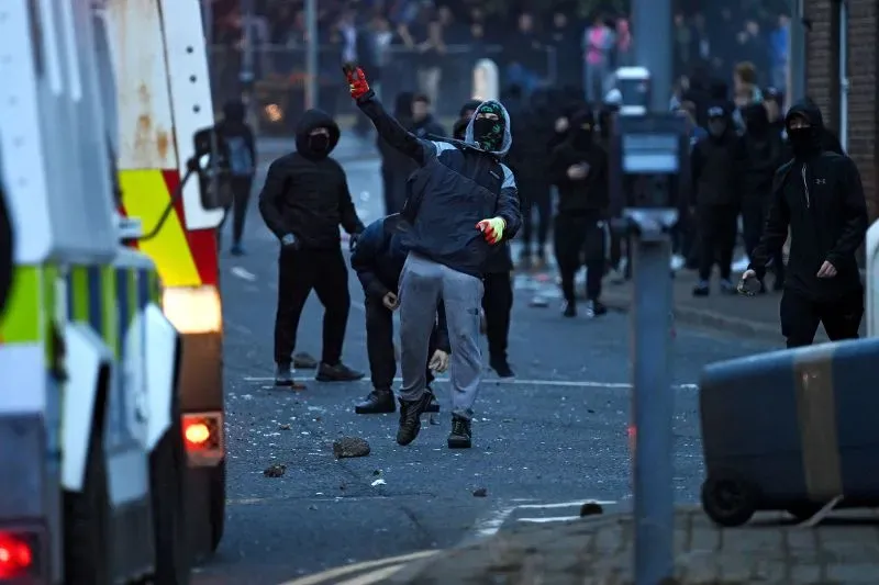 شخص ملثم يرمي حجارة نحو الشرطة خلال أعمال شغب في باليمينا، أيرلندا الشمالية، حيث شهدت البلدة تصاعدًا في العنف عقب احتجاجات.