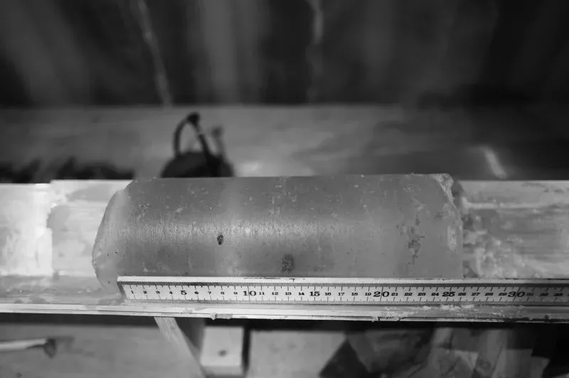 لب جليدي بطول 3.2 قدم مُستخرج من القارة القطبية الجنوبية، مع مسطرة لقياس الطول، يمثل جزءًا من مشروع بحثي لدراسة مناخ الأرض.