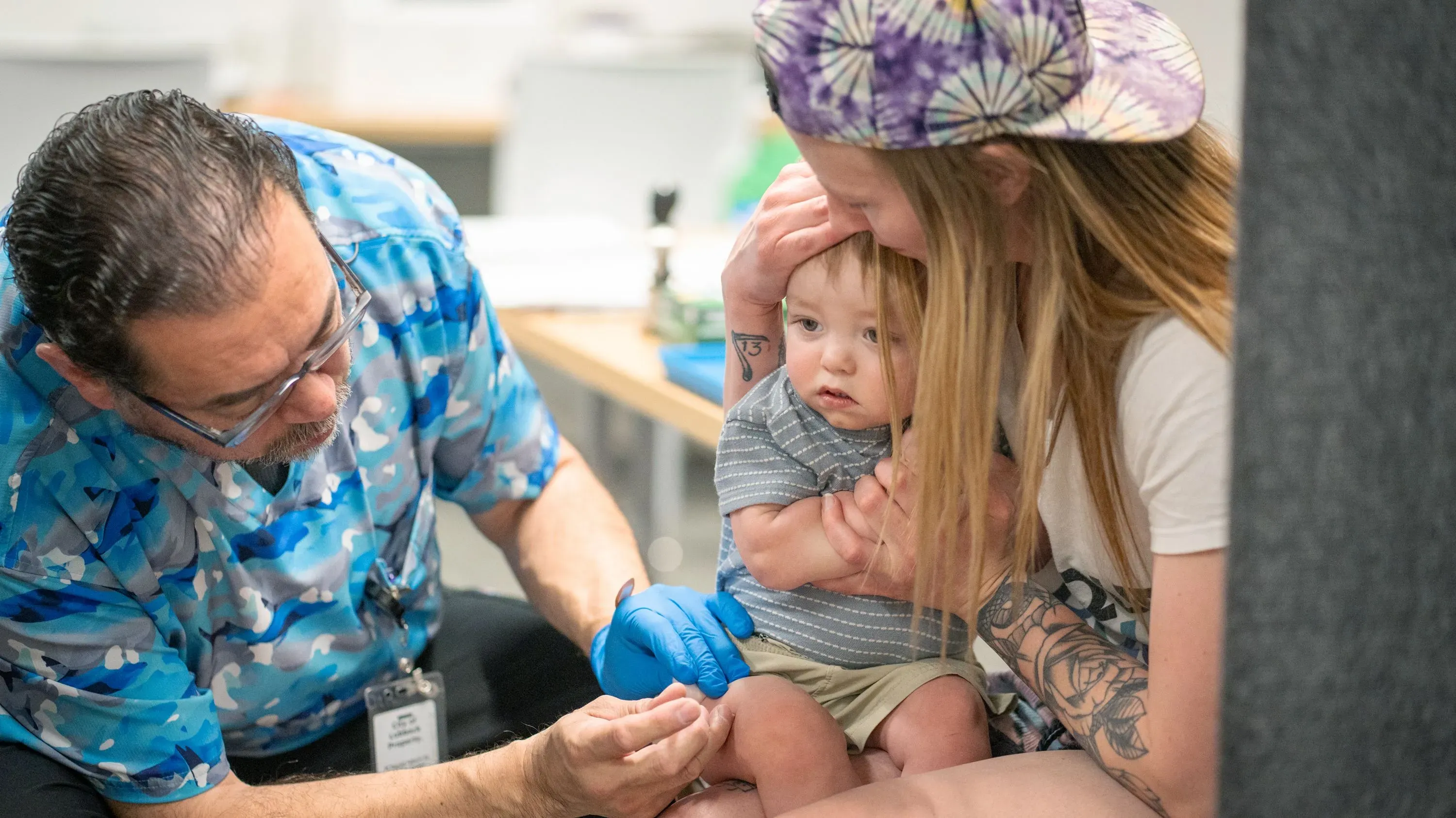 طفل صغير يتلقى لقاح الحصبة من طبيب، بينما تحتضنه والدته، مما يسلط الضوء على أهمية التطعيم ضد الأمراض المعدية.