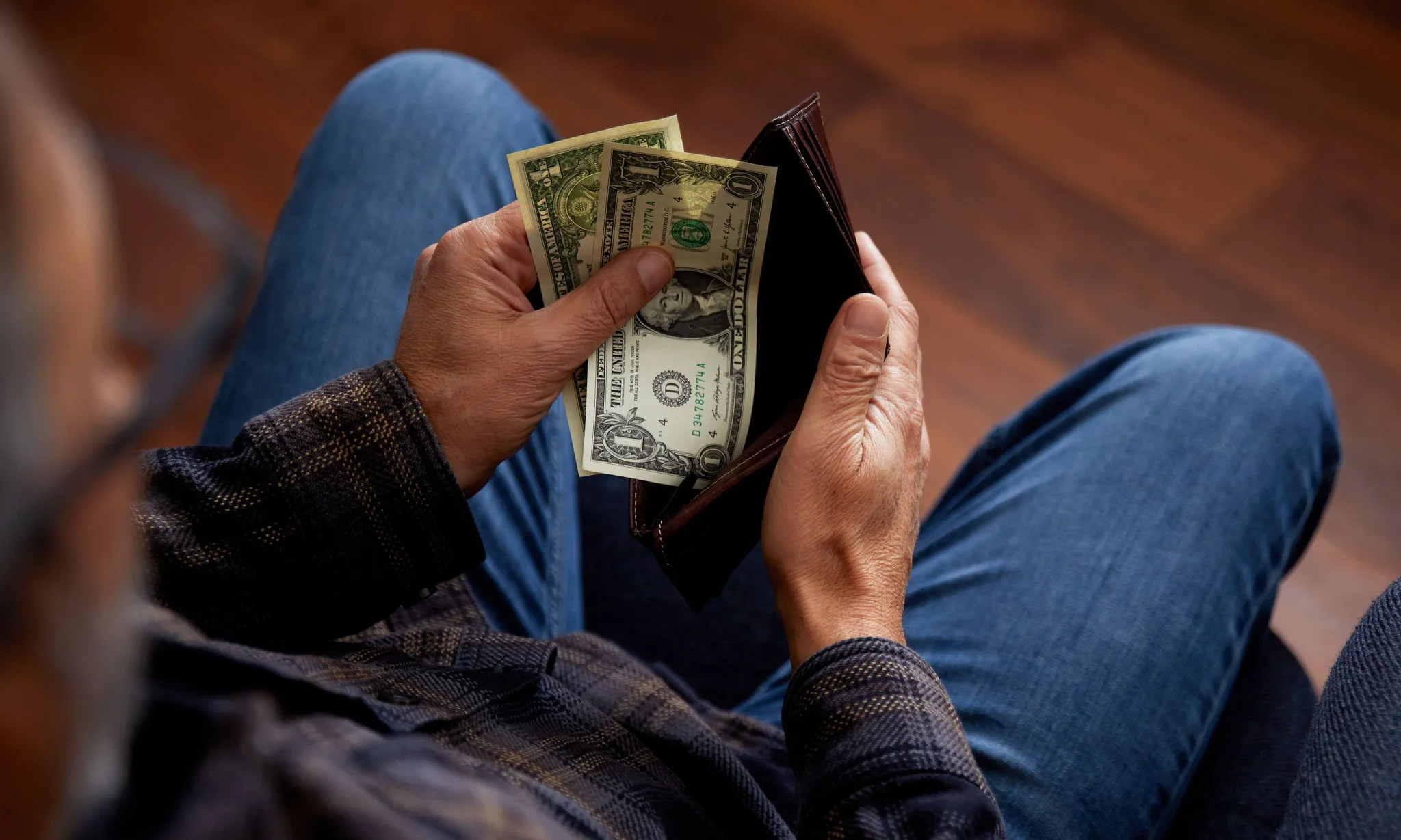 يد شخص يحمل محفظة نقدية بها أوراق دولار أمريكي، مع التركيز على موضوع دخل الأسرة الأمريكية والتفاوت الاقتصادي في 2025.