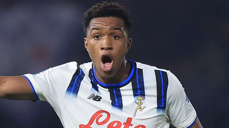 لاعب كرة قدم شاب يرتدي قميص أتالانتا يعبر عن حماس أثناء مباراة، مع تسليط الضوء على انتقاله المرتقب إلى تشيلسي بصفقة مالية كبيرة.