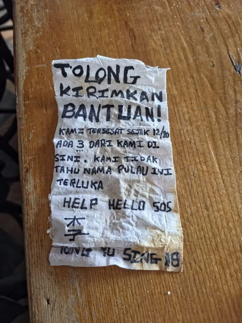 رسالة استغاثة مكتوبة بخط اليد داخل زجاجة، تحتوي على طلب مساعدة من طاقم مفقود، مع ذكر اسم السفينة "يونغ يو سينغ رقم 18".