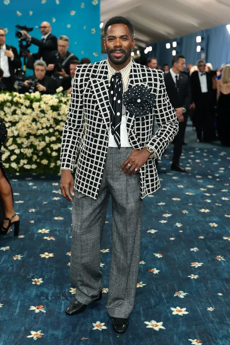 رجل يرتدي بدلة متباينة الألوان مع نمط مربعات، يتوسط حفل الميت غالا في متحف متروبوليتان، محاطاً بالضيوف.