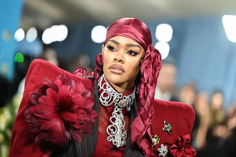 تظهر الصورة نجمة ترتدي فستانًا جريئًا باللون الأحمر مع تفاصيل مزخرفة، خلال حفل الميت غالا في متحف المتروبوليتان.