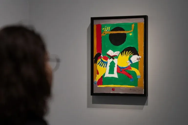 لوحة فنية ملونة لمقبول فدا حسين تعرض شخصية على حصان، مع خلفية خضراء وعناصر عربية تقليدية، في متحف "لوح وقلم" بالدوحة.