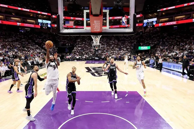 لاعب من فريق دالاس مافريكس يسجل نقطة في مباراة ضد ساكرامنتو كينجز، مع جمهور خلفه في ملعب كرة السلة.