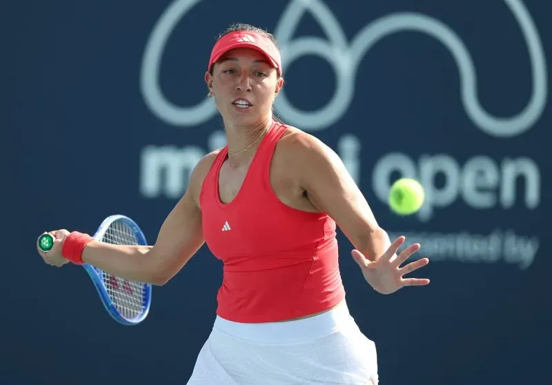 لاعبة تنس ترتدي زيًا أحمر، تستعد لضرب كرة التنس خلال بطولة ميامي المفتوحة. تعكس الصورة التوتر والتركيز في المباراة.