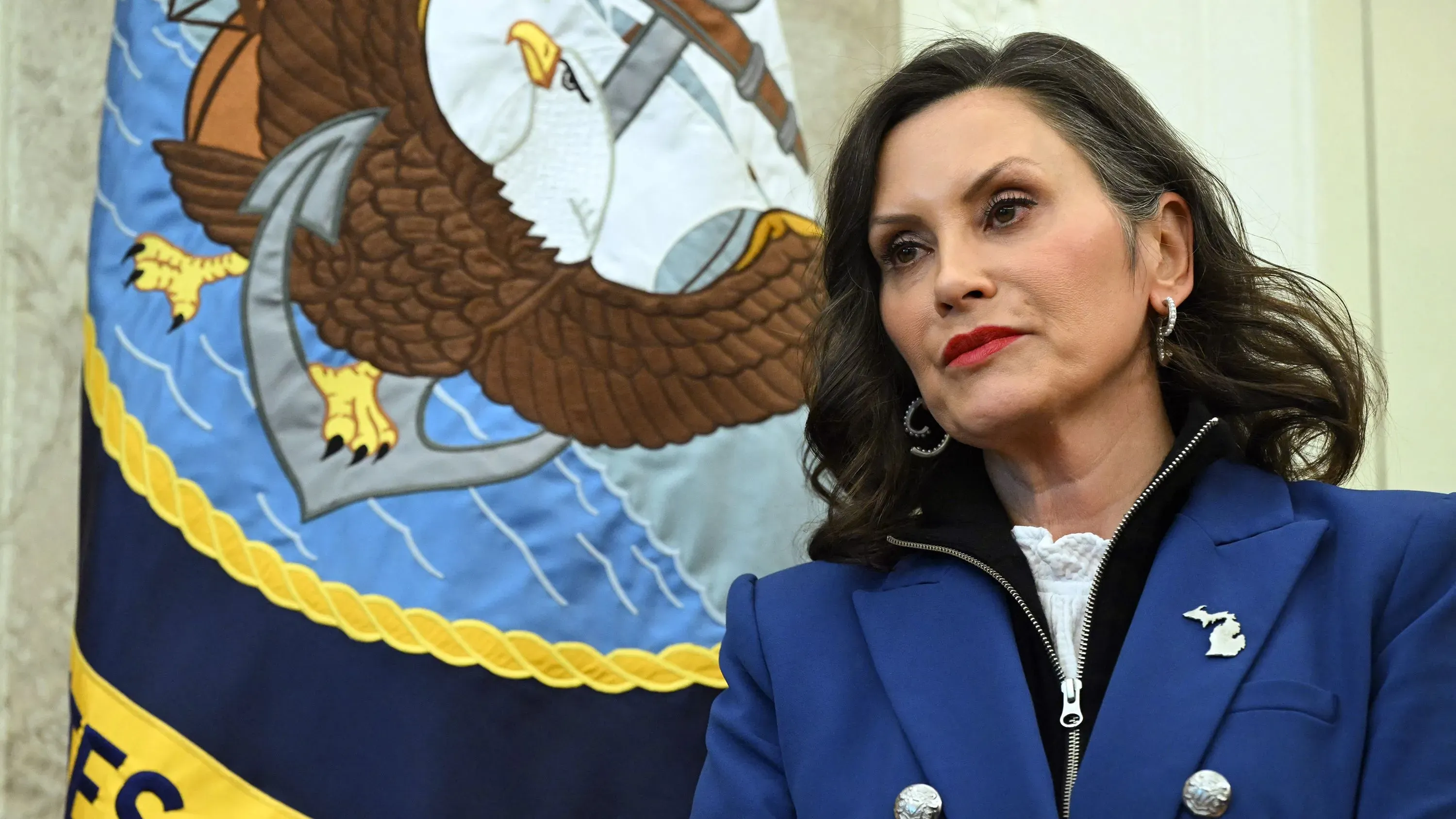 حاكمة ميشيغان غريتشن ويتمير تتحدث بجدية، مع العلم بشعار الولاية خلفها، وسط نقاش حول إمكانية عفو ترامب عن المدانين بمؤامرة اختطافها.