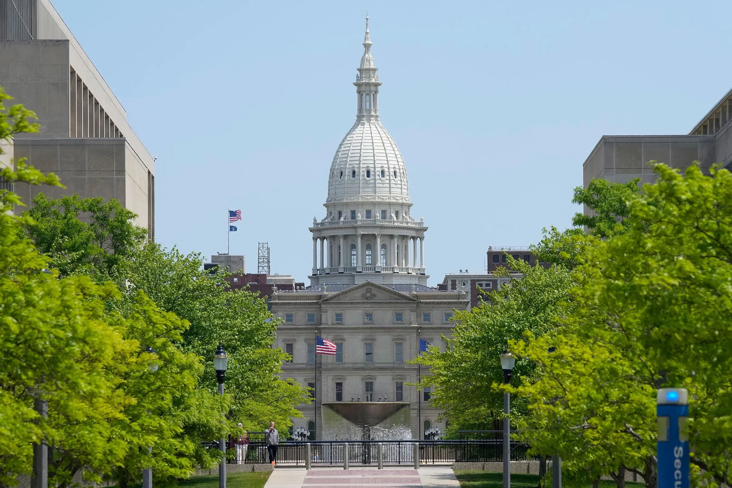 مبنى الكابيتول في ولاية ميشيغان يظهر وسط الأشجار الخضراء، يرمز إلى الأحداث القانونية المتعلقة بانتخابات 2020.