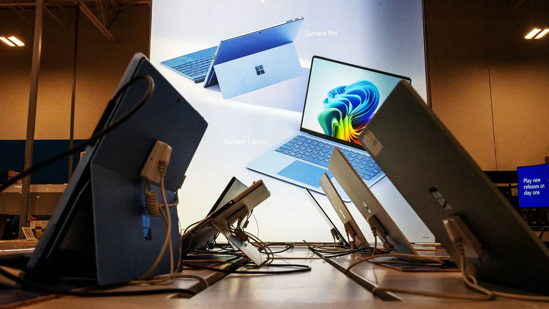 أجهزة كمبيوتر محمولة من مايكروسوفت مع شاشة تعرض معلومات عن منتجات Surface، تعكس الابتكار التكنولوجي في الشركة.