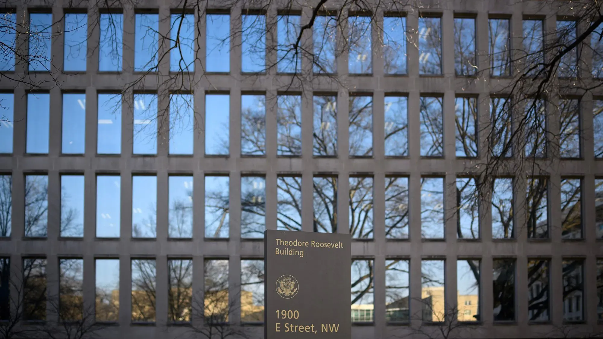 واجهة مبنى ثيودور روزفلت، مع لافتة تحمل عنوان المبنى وعنوانه، تعكس التوترات حول توجيهات العمل عن بُعد للأزواج العسكريين.