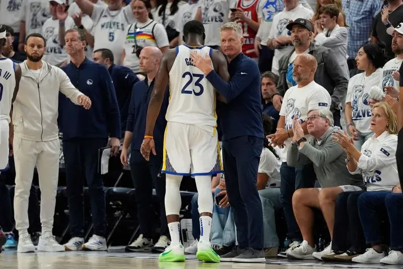 مدرب فريق غولدن ستيت ووريورز يتحدث مع أحد لاعبيه بعد المباراة، حيث يظهر جمهور متحمس يرتدي قمصان الفريق.