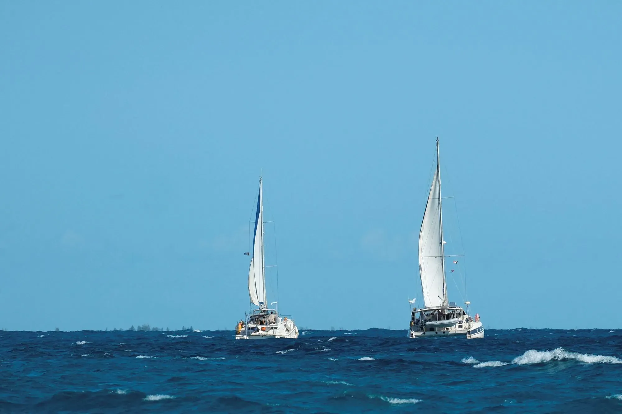 زورقان شراعيان مكسيكيان يبحران في البحر الكاريبي، جزء من قافلة مساعدات إنسانية إلى كوبا، تحت سماء زرقاء.