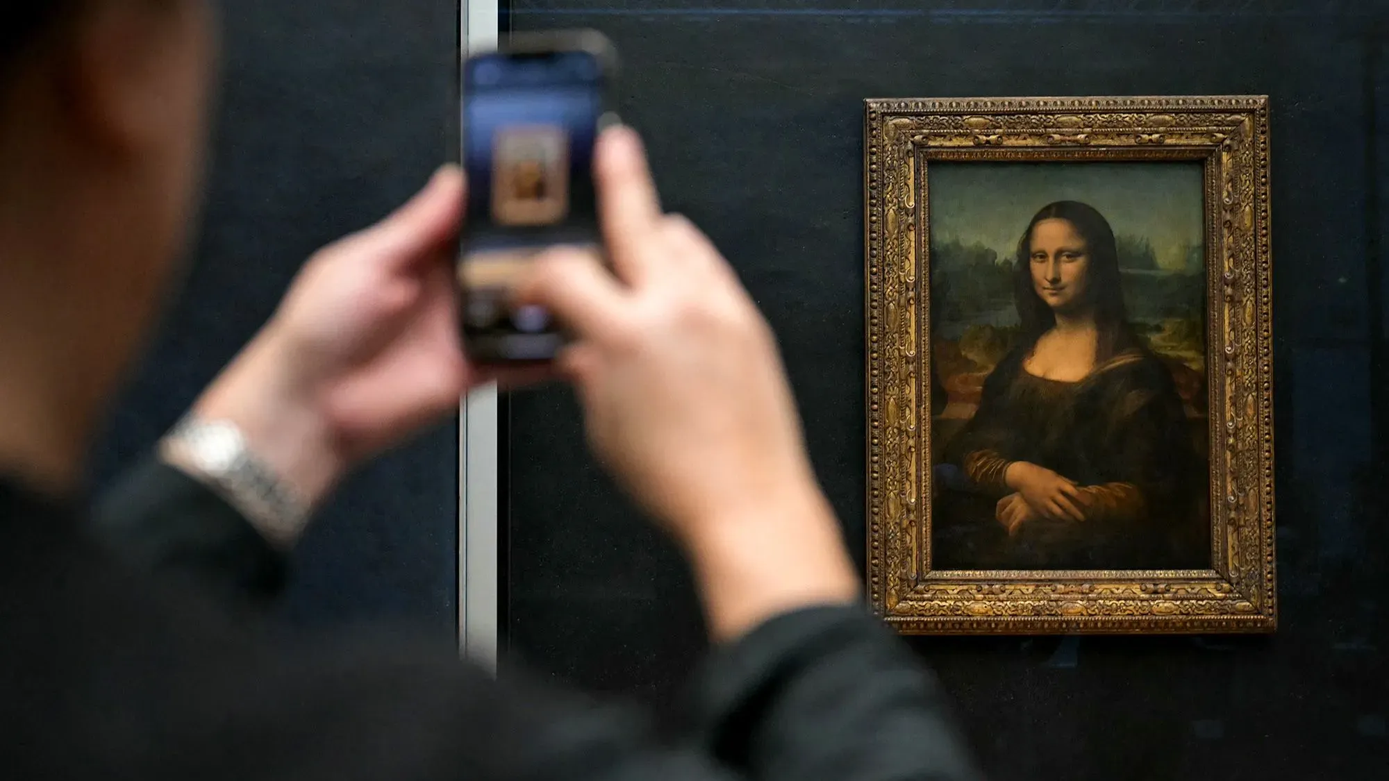 شخص يلتقط صورة للوحة "الموناليزا" في متحف اللوفر، حيث ستخضع للتحديث والتوسيع لجعل الزيارة أكثر سهولة للزوار.