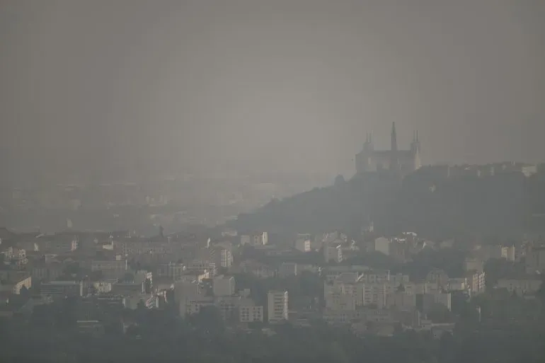 صورة لمدينة مغطاة بالضباب، مع معالم معمارية واضحة في الخلفية، تعكس تأثير التغير المناخي على جودة الهواء.