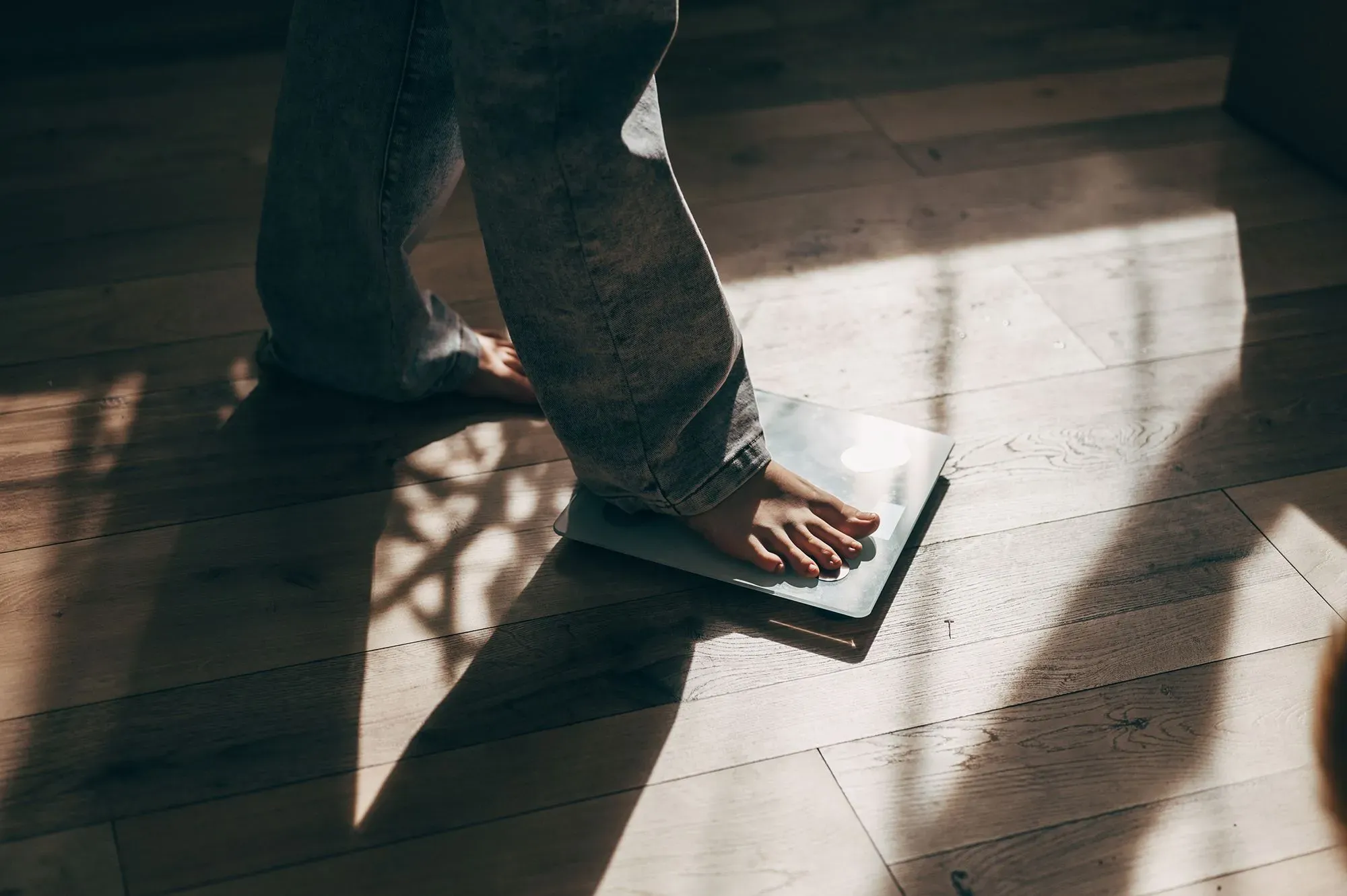 طفل يقف على ميزان في غرفة مضاءة بأشعة الشمس، يعكس زيادة الوزن والسمنة كقضية صحية متزايدة وفقًا لتقرير اليونيسف.