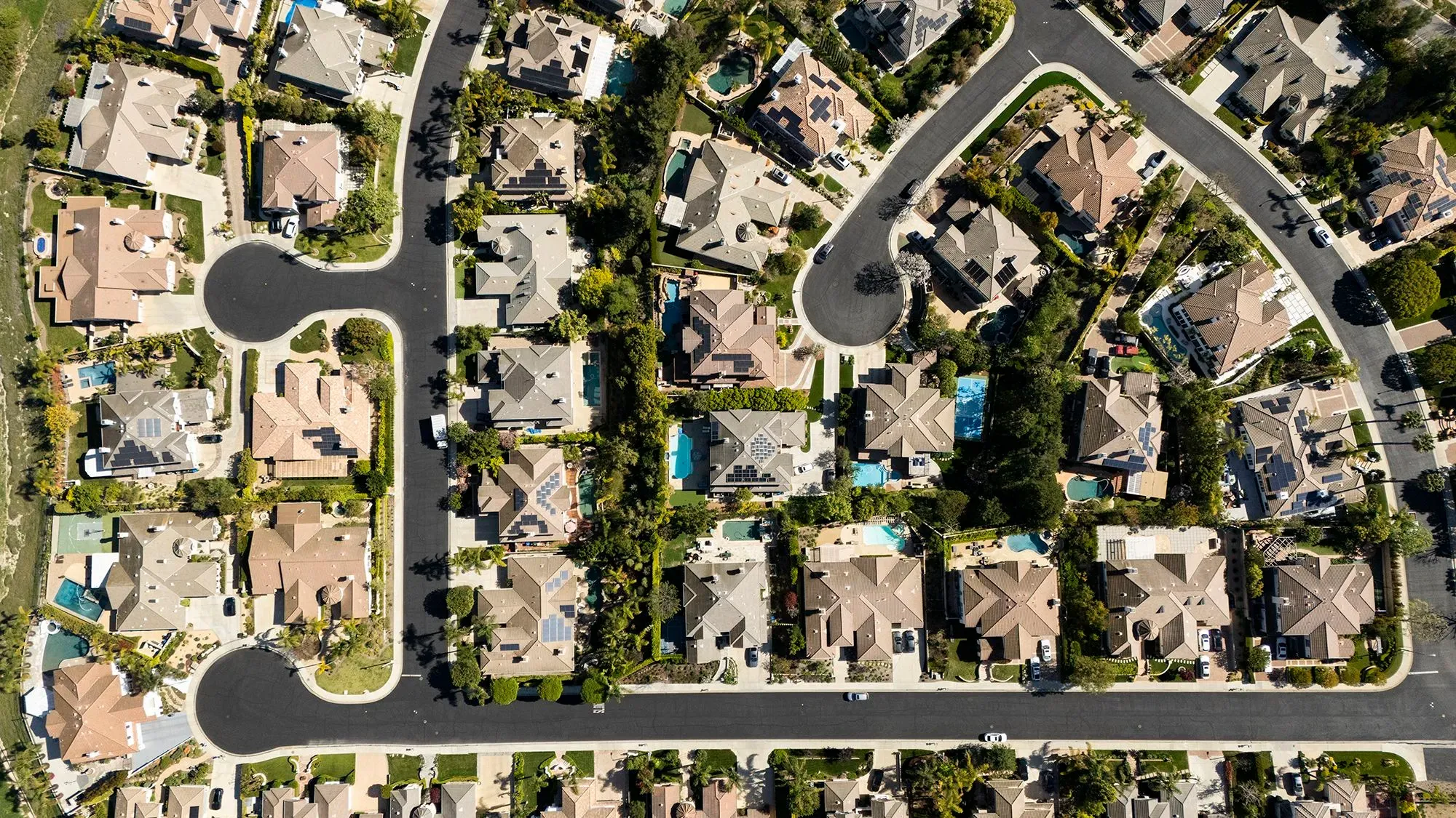 مشهد جوي لحي سكني يتضمن منازل متعددة مع مسارات طرق متعرجة، يعكس تأثير معدلات الرهن العقاري المرتفعة على سوق الإسكان.