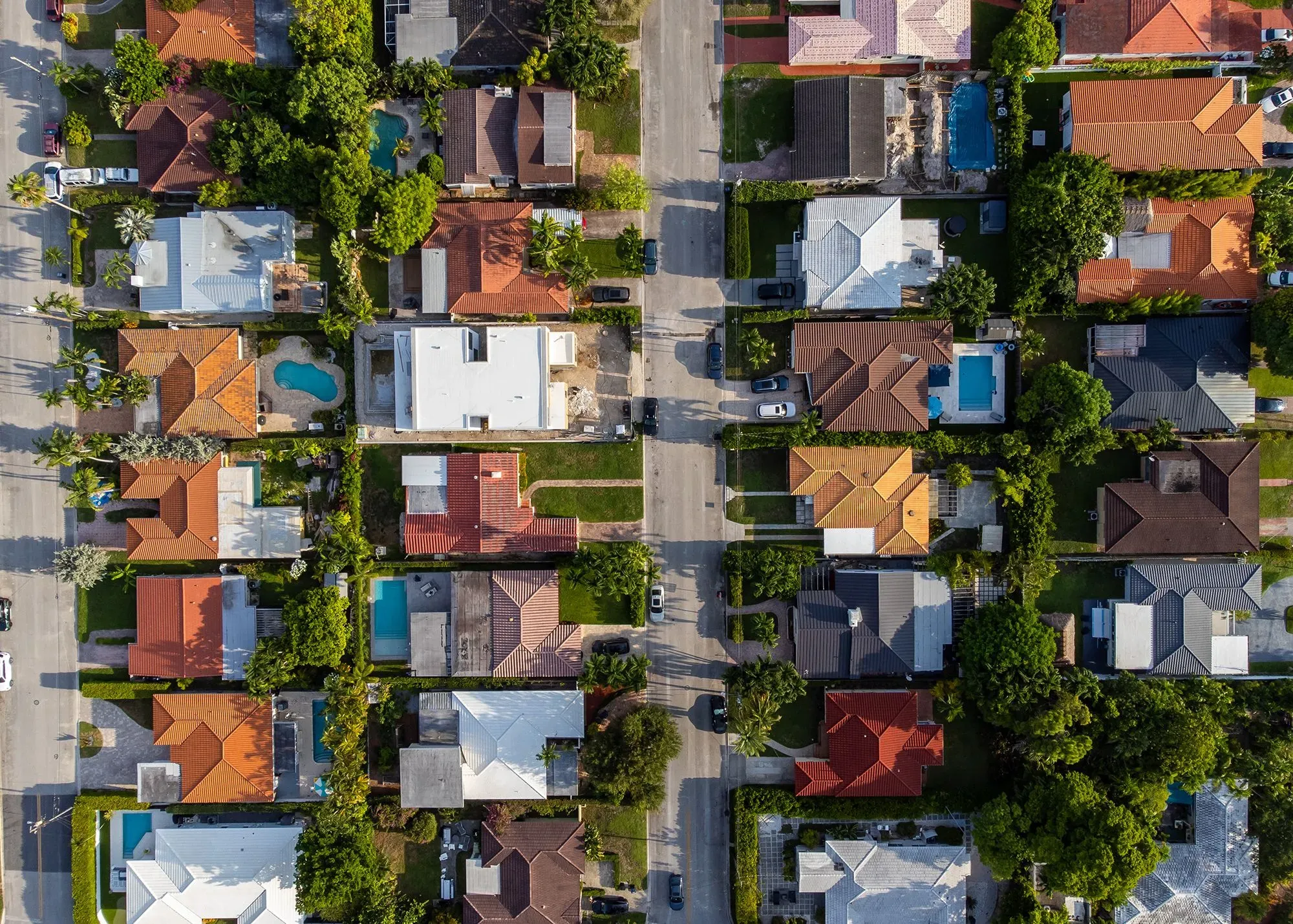 منظر جوي لمجموعة من المنازل في حي سكني، يظهر الشوارع والأشجار، ويعكس حالة سوق الإسكان المتغير.