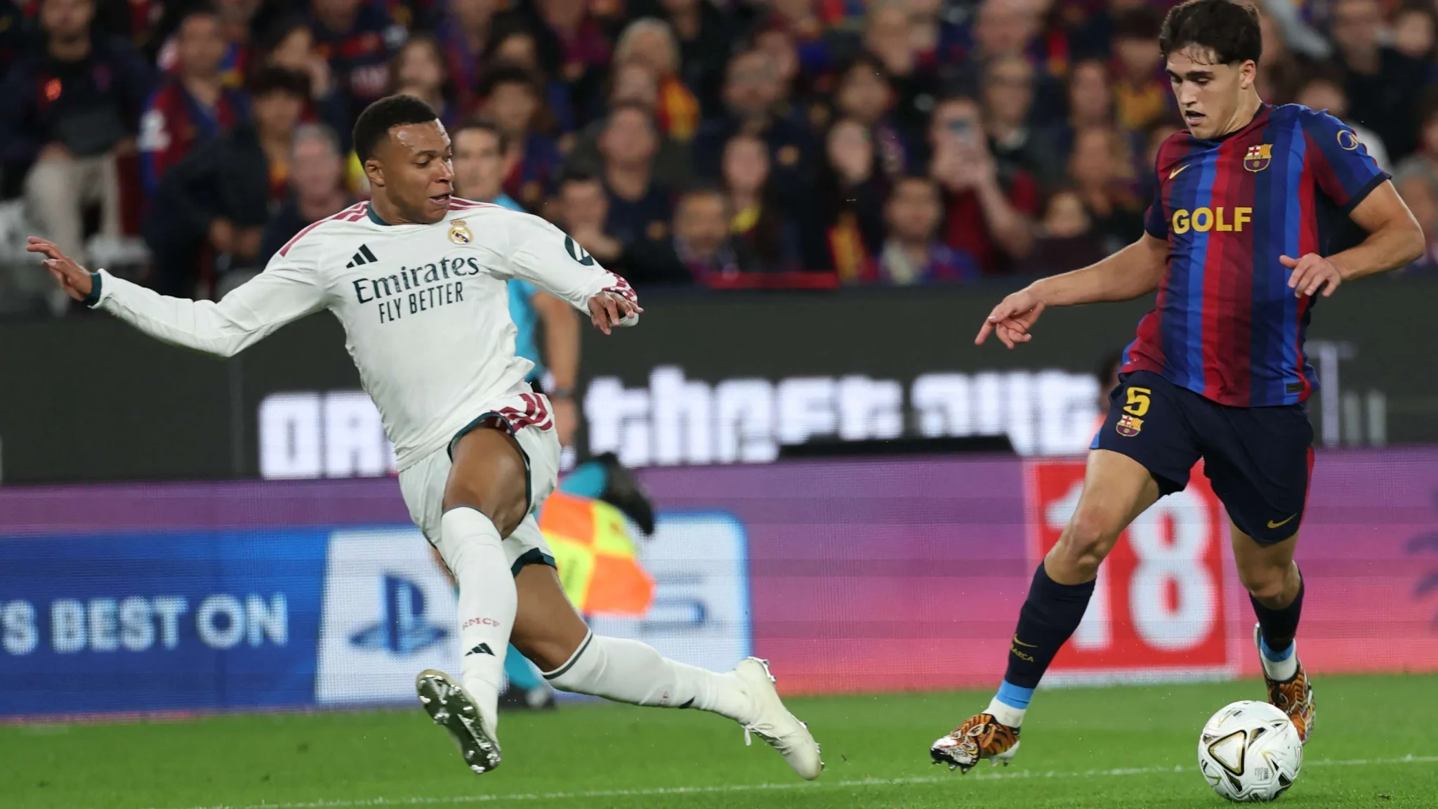 لاعب ريال مدريد يقطع الكرة من لاعب برشلونة خلال مباراة حاسمة في الدوري الإسباني مع ضغط دفاعي متقدم من الفريقين.
