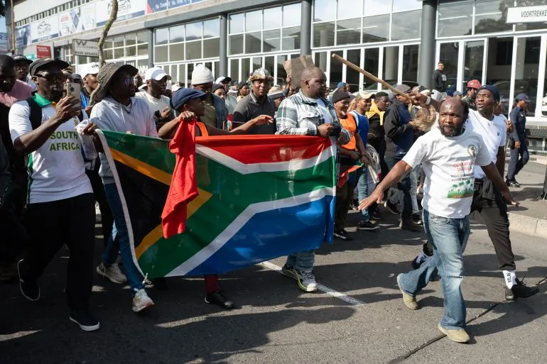 مظاهرة في Mossel Bay، حيث يحمل المشاركون علم جنوب أفريقيا، تعبيرًا عن الاحتجاجات ضد الهجرة والعنف الموجه ضد المهاجرين.