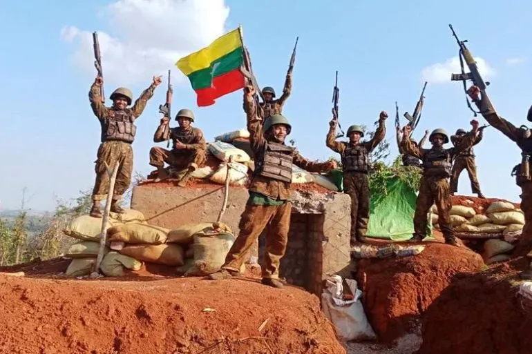 جنود من الجيش في ميانمار يحتفلون بعد استعادة السيطرة على بلدة ناونغكيو، رافعين الأسلحة وعلم البلاد، في سياق المعركة ضد المتمردين.