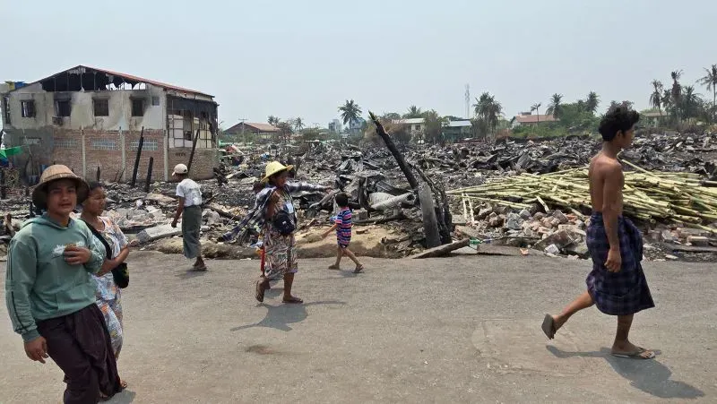 تظهر الصورة مشهدًا مأساويًا في ميانمار بعد الزلزال المدمر، حيث يسير السكان بين الأنقاض والمنازل المدمرة، مما يعكس حجم الكارثة الإنسانية.