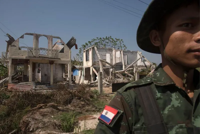 جندي يقف أمام منازل مدمرة في ميانمار بعد زلزال قوي، مما يعكس الأزمة الإنسانية المستمرة وتأثير الحرب الأهلية.