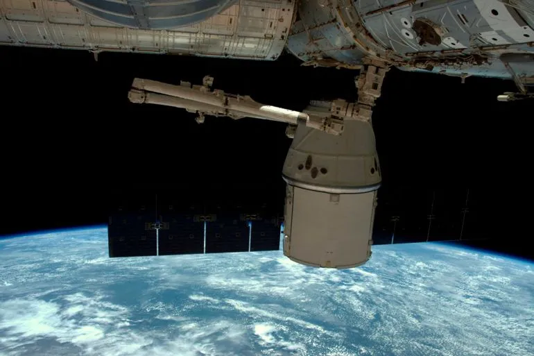 مركبة Dragon التابعة لـ SpaceX متصلة بمحطة الفضاء الدولية، مع رؤية لكوكب الأرض في الخلفية، في سياق إصلاحات تسرّبات هواء.