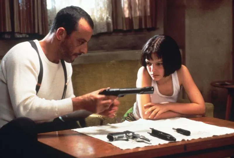 مشهد من فيلم "المحترف" يظهر شخصية ناتالي بورتمان وهي تتفاعل مع شخصية جان رينو أثناء مناقشة الأسلحة، مما يبرز بداية مسيرتها الفنية.