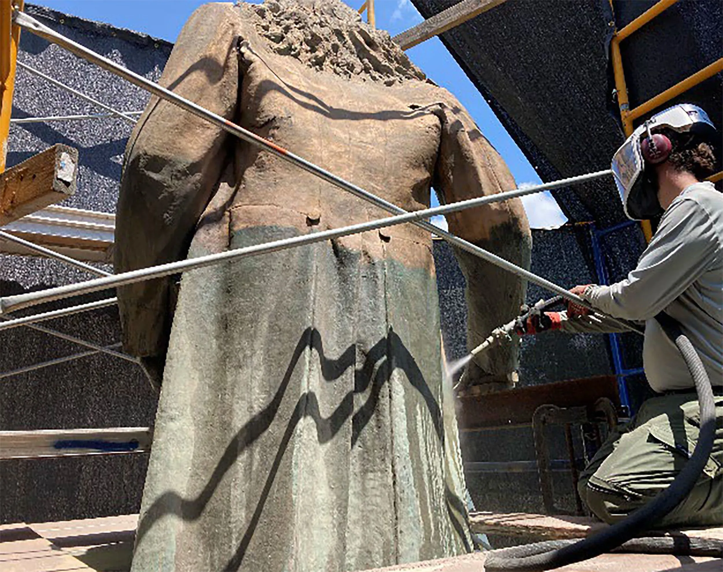 ترميم تمثال ضابط كونفدرالي في واشنطن، مع عامل يستخدم معدات لتنظيفه، في إطار جهود إعادة التركيب بعد إزالة التمثال.