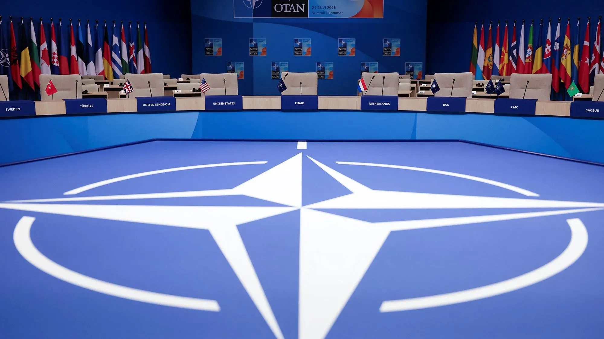 اجتماع قادة الناتو مع العلم الخاص بالتحالف على الطاولة، حيث يناقش الأعضاء زيادة الإنفاق الدفاعي لمواجهة التحديات الأمنية.