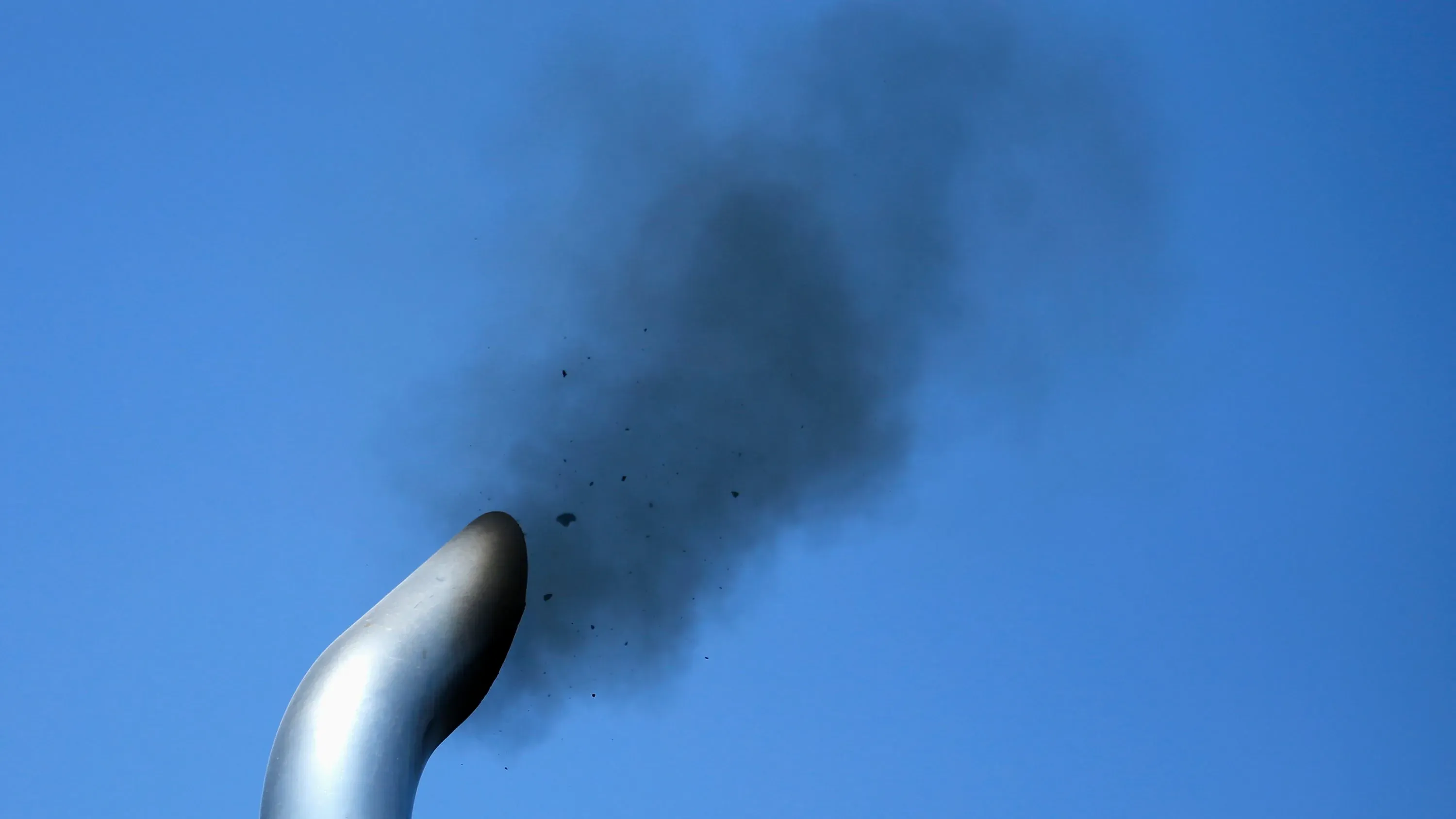 دخان أسود يتصاعد من أنبوب عادم، مما يعكس تلوث الهواء الناتج عن انبعاثات المركبات والمصادر الصناعية.