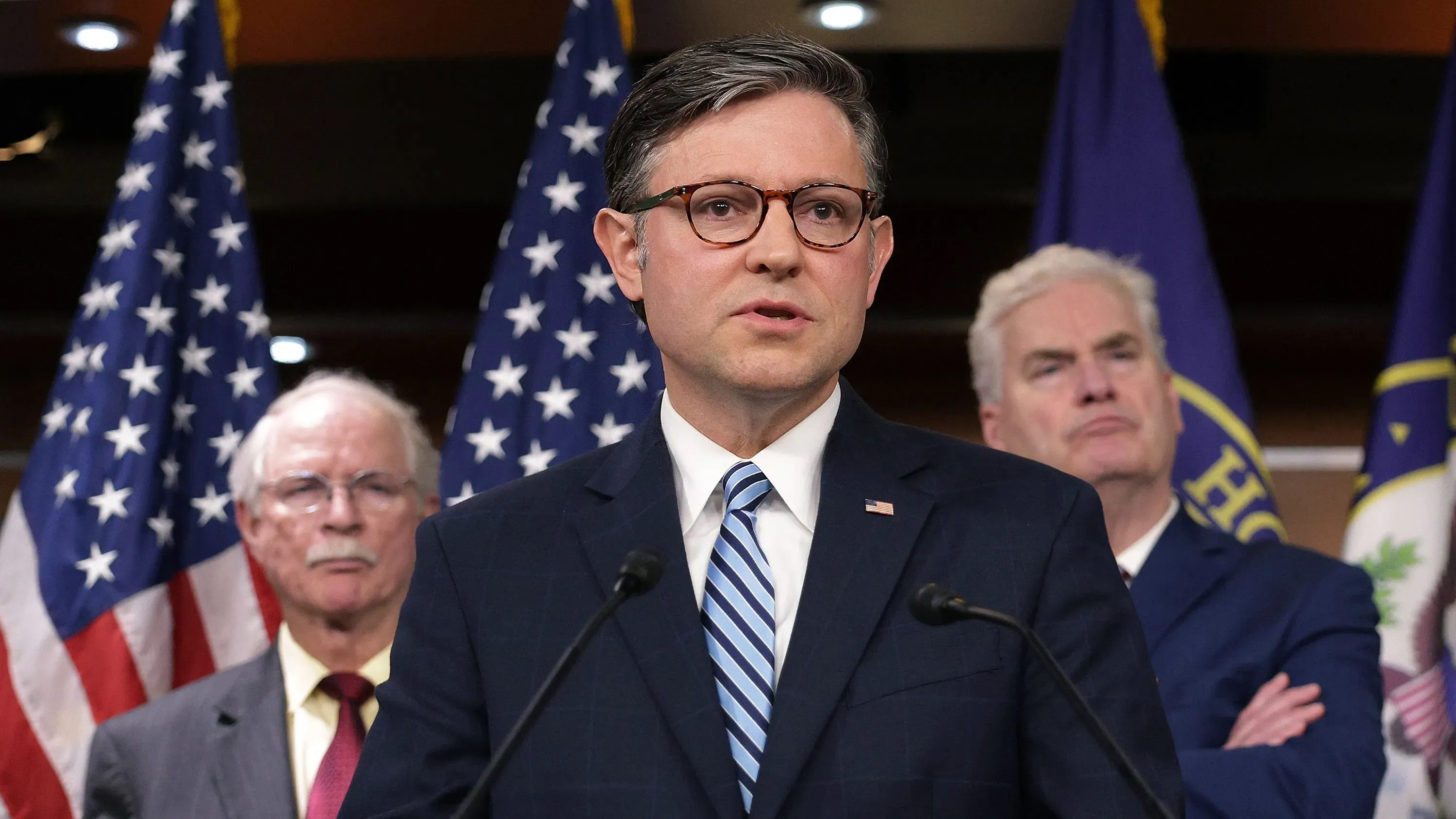 تظهر الصورة مسؤولًا جمهوريًا يتحدث في مؤتمر صحفي، مع أعلام خلفه، في سياق مناقشات حول مشروع قانون تخفيض الضرائب والإنفاق.